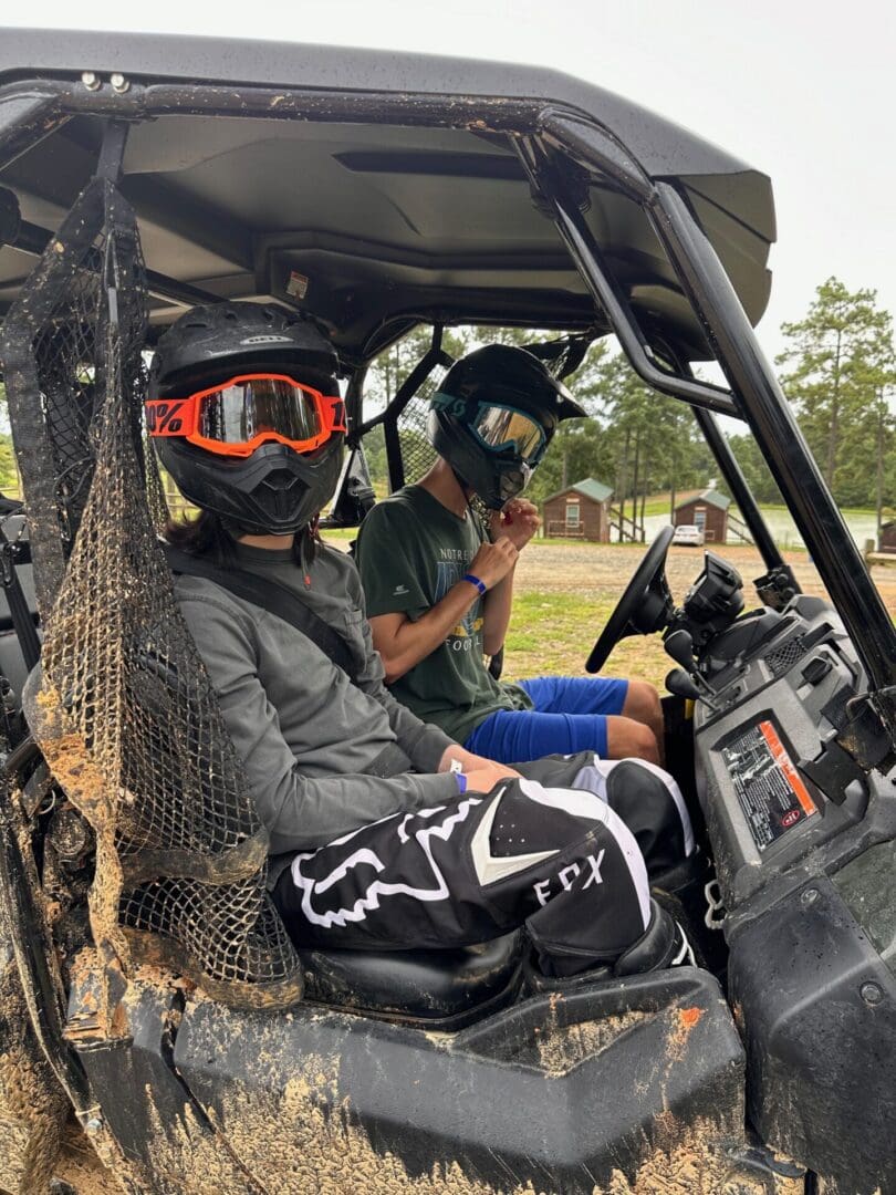 Two helmeted riders seated in a side-by-side during a Winnsboro trip