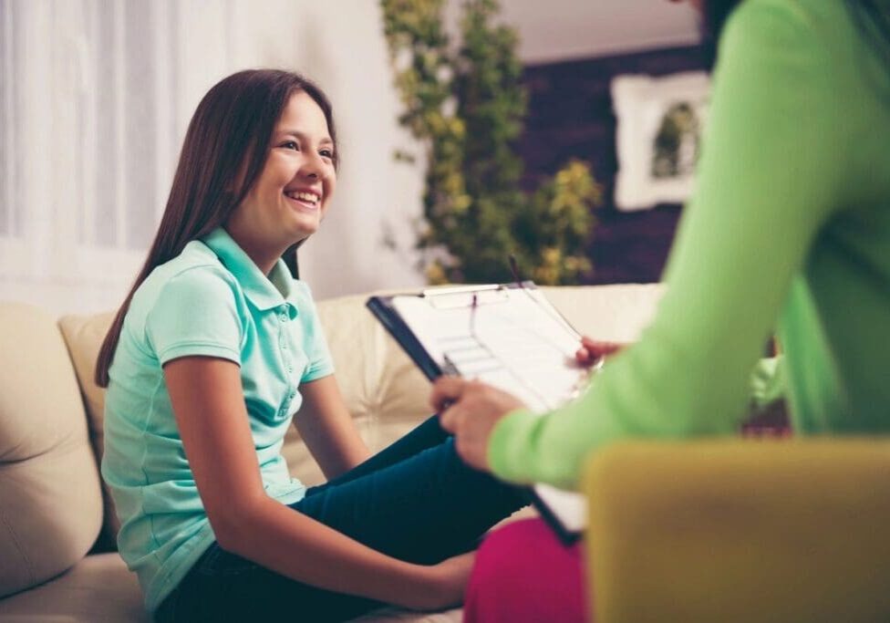 A girl sitting on the couch with another girl.